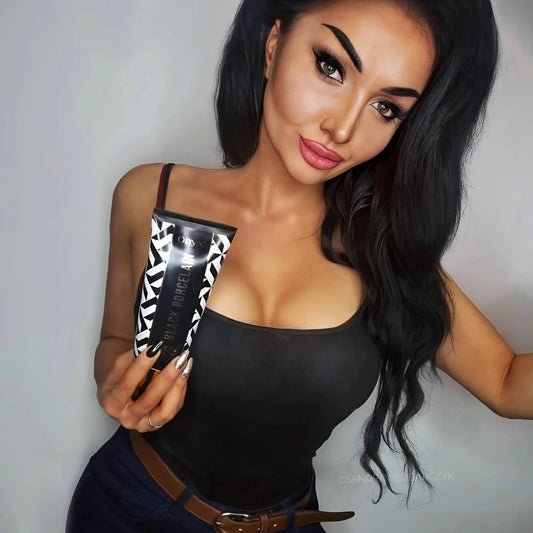 Mujer con largo cabello negro sostiene la loción Onyx Black Porcelain frente a un fondo claro, elegante y glamurosa