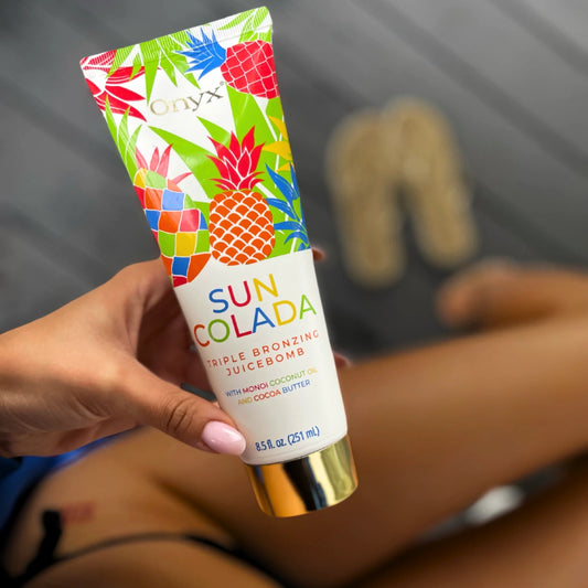 Mano sostiene Suncolada loción bronceadora, fondo desenfocado