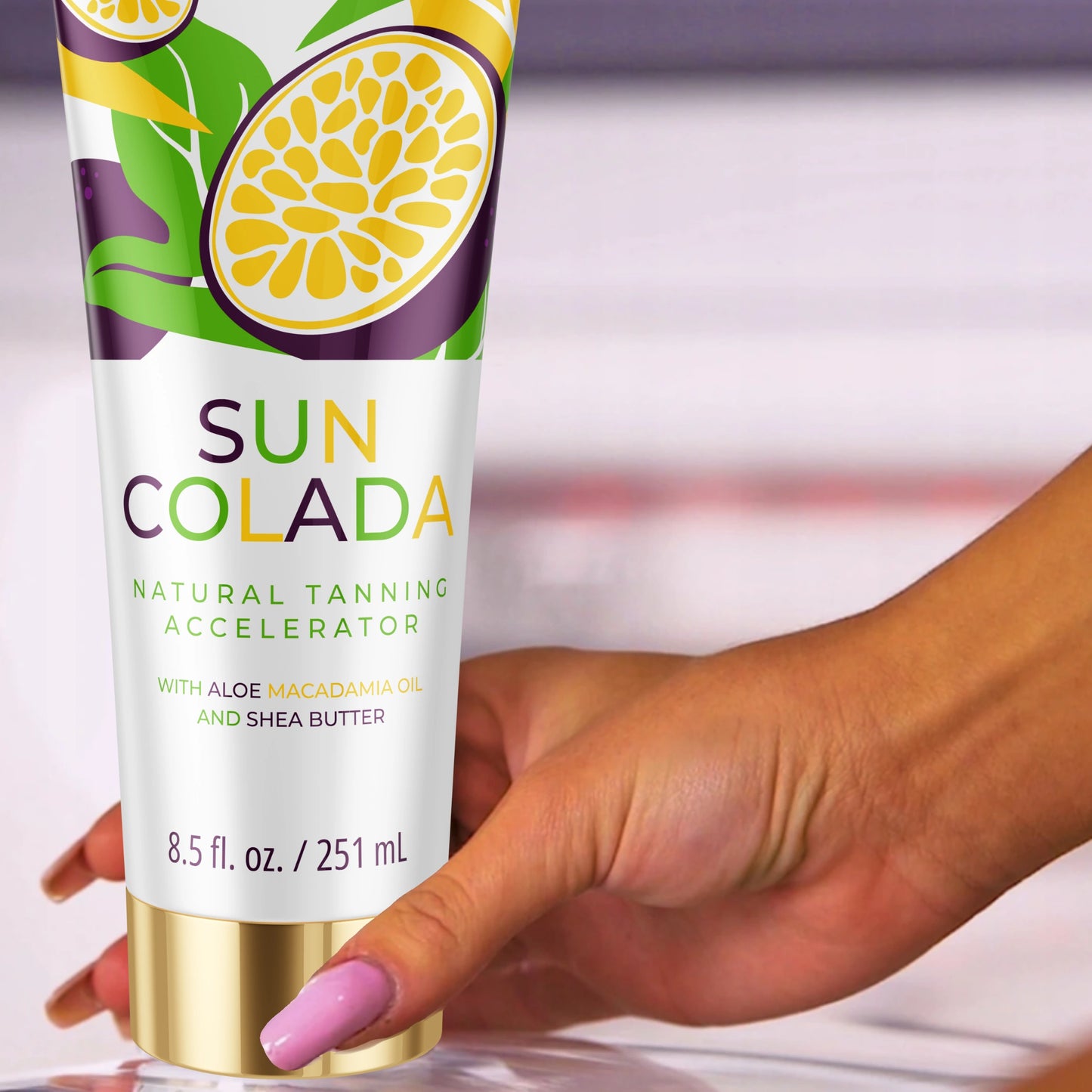 Mano sosteniendo la loción bronceadora Onyx Suncolada con envase blanco y dorado, infusionada con manteca de karité y aceite de macadamia para un acelerador de bronceado ultra hidratante