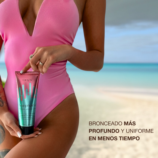 Mujer en bañador rosa en la playa sosteniendo Onyx Sunphoria, crema aceleradora de bronceado para un tono más profundo y uniforme en menos tiempo.