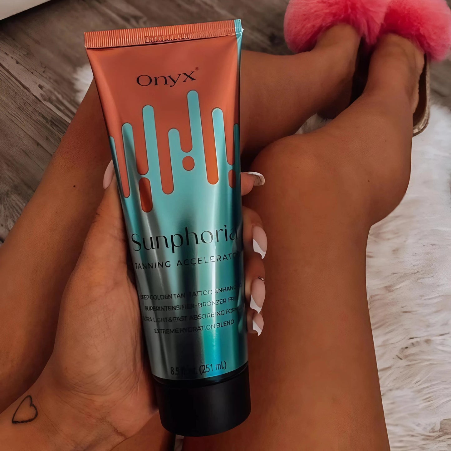 Primer plano de la Loción Onyx Sunphoria sobre piernas bronceadas con piel blanca de fondo