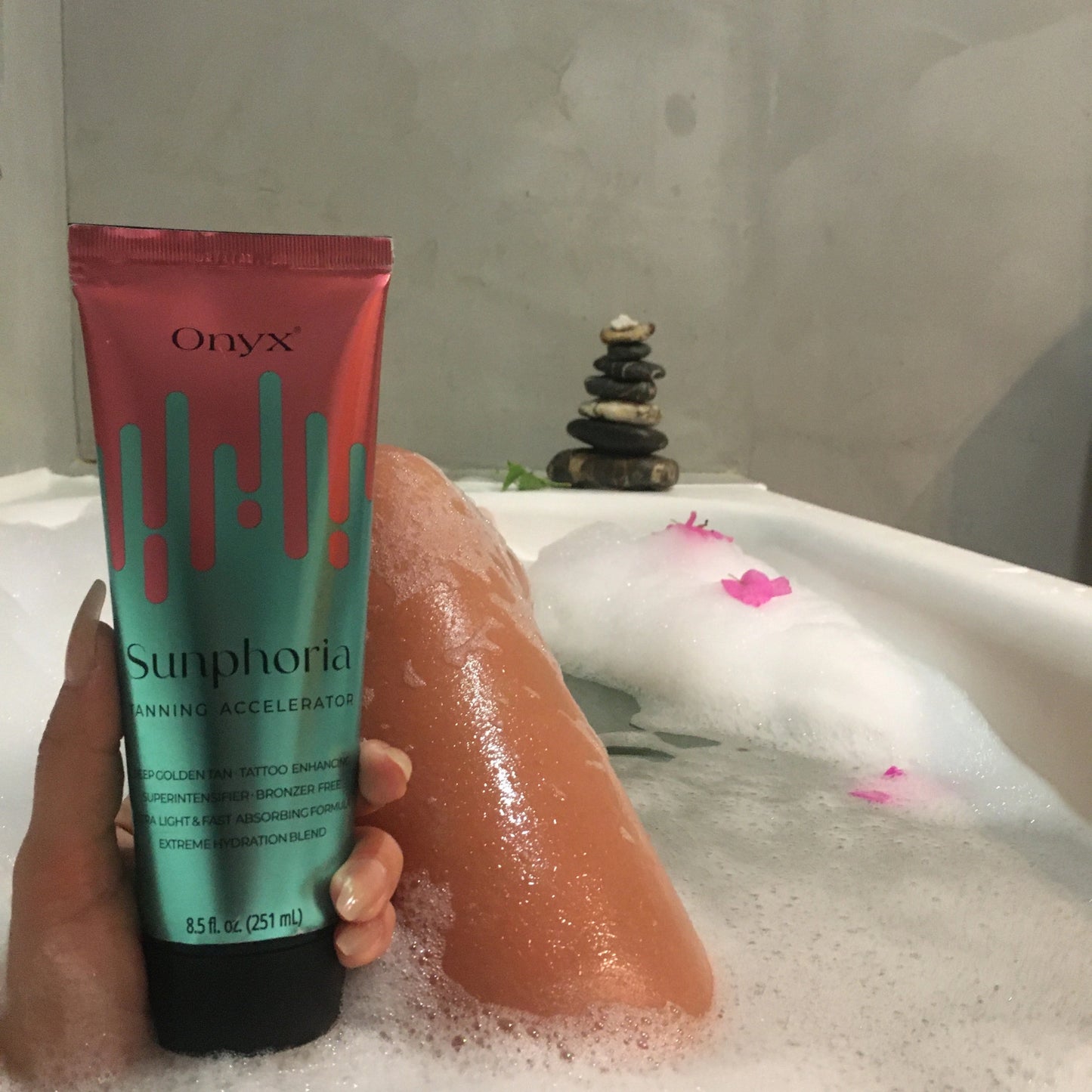 Loción Bronceadora Onyx Sunphoria en una bañera con espuma y flores