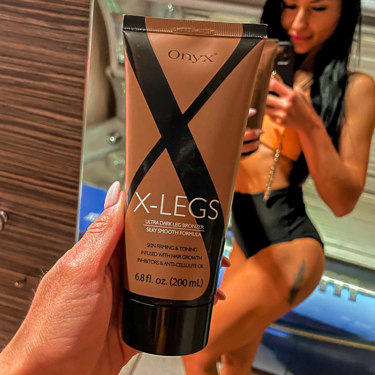 Mujer con piernas bronceadas sostiene la loción Onyx X-LEGS en el solarium