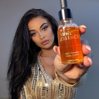 Mujer con cabello largo y negro muestra el frasco de las Gotas Sunl’essence a la cámara