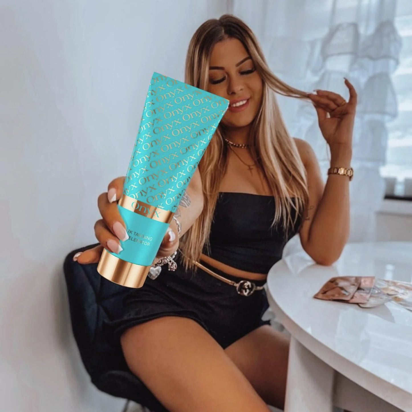 Mujer sonriendo y mostrando Onyx Dark Tanning Accelerator crema bronceadora con efecto hidratante y bronceado natural