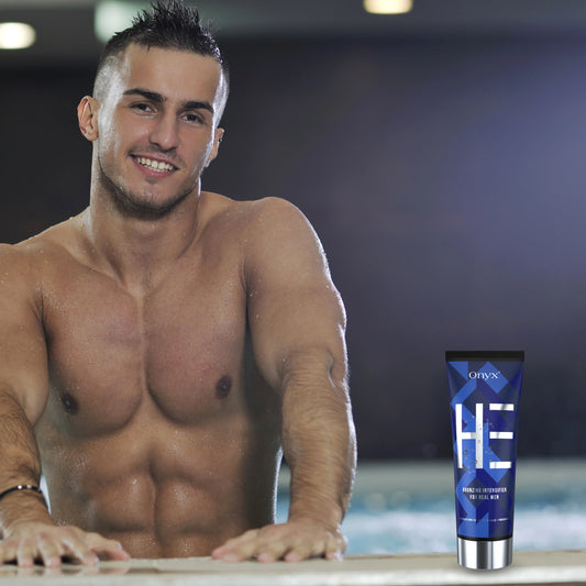 Hombre sonriendo en un salón de bronceado sosteniendo Onyx HE Bronzing Lotion: acelerador de bronceado profesional para hombres.