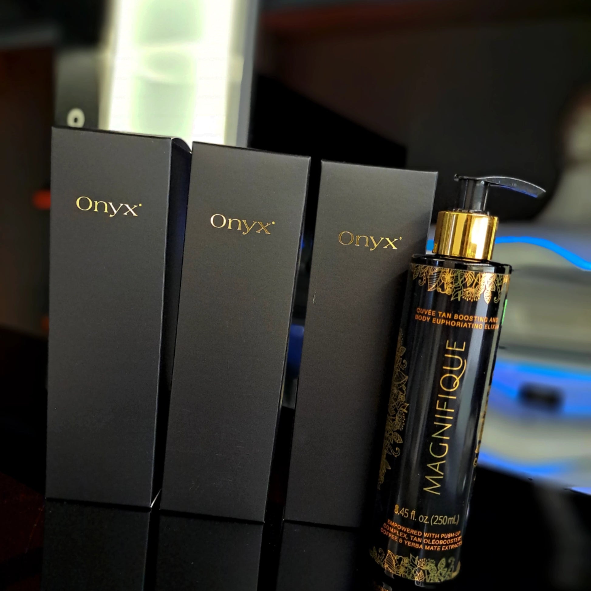 Onyx Magnifique Elixir Bronceador junto a tres elegantes cajas negras – diseño sofisticado para un cuidado de alta calidad