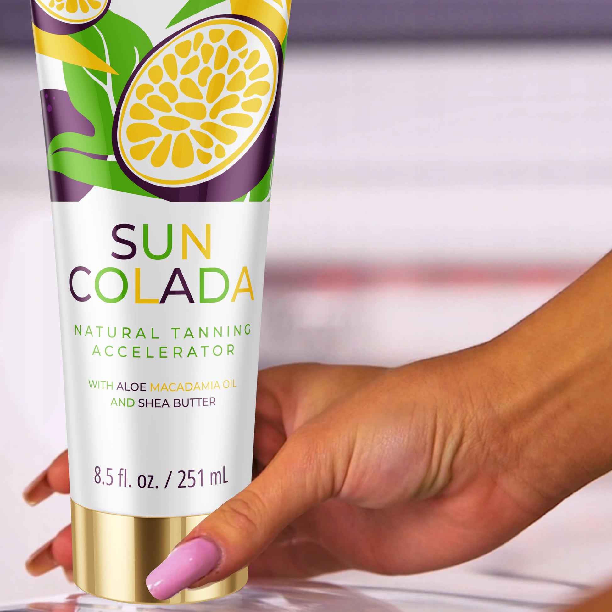 Mano sosteniendo la loción bronceadora Onyx Suncolada con envase blanco y dorado, infusionada con manteca de karité y aceite de macadamia para un acelerador de bronceado ultra hidratante