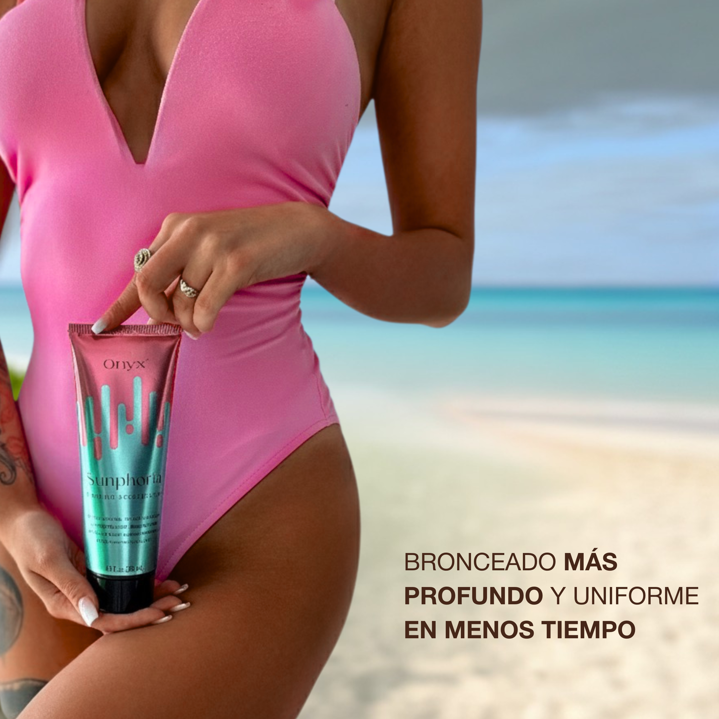 Mujer en bañador rosa en la playa sosteniendo Onyx Sunphoria, crema aceleradora de bronceado para un tono más profundo y uniforme en menos tiempo.