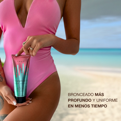 Mujer en bañador rosa en la playa sosteniendo Onyx Sunphoria, crema aceleradora de bronceado para un tono más profundo y uniforme en menos tiempo.